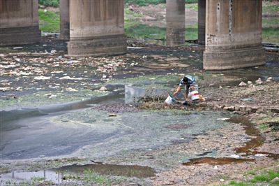 5月27日，一位村民正被嚴重污染的南沙河河道里打水準備澆菜，其下游不遠處，即是沙河水庫。新京報記者 周崗峰 攝